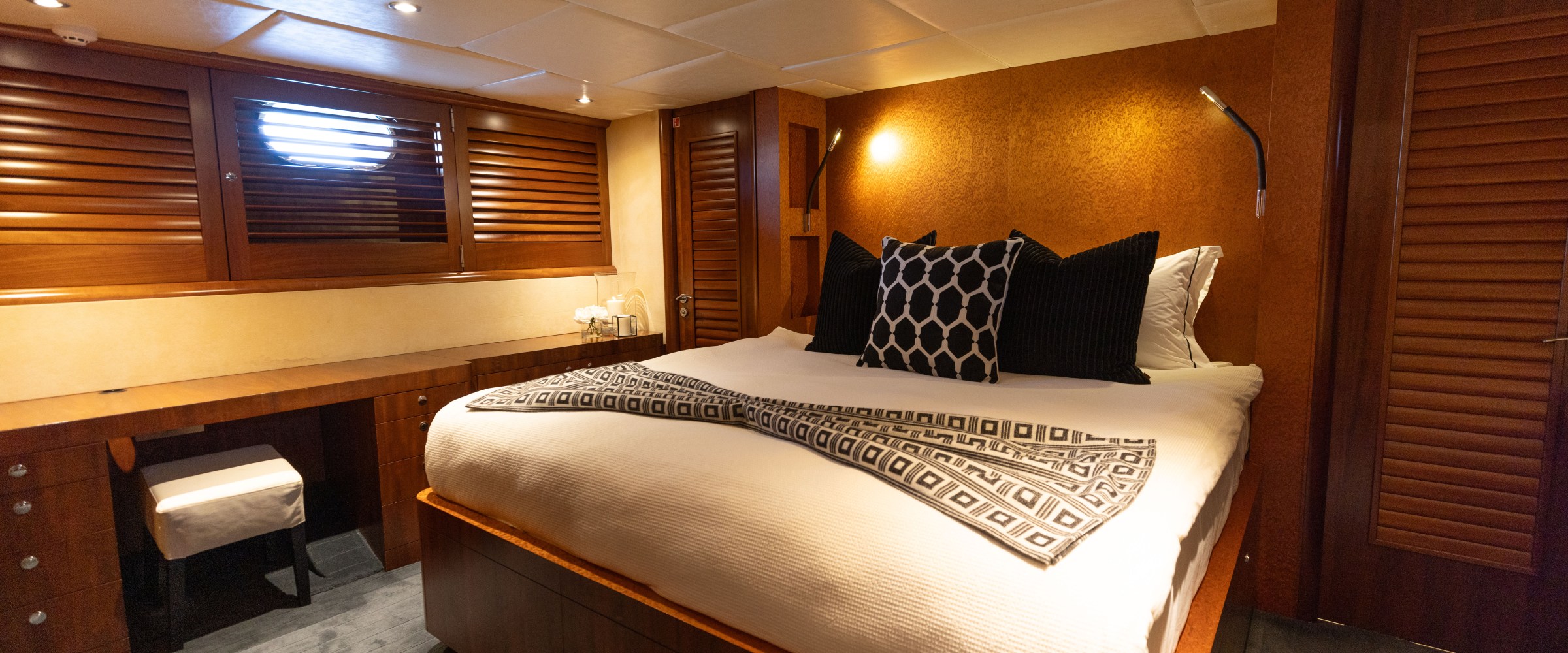 Luxurious boat cabin with double bed, pillows, desk, and wooden paneling.