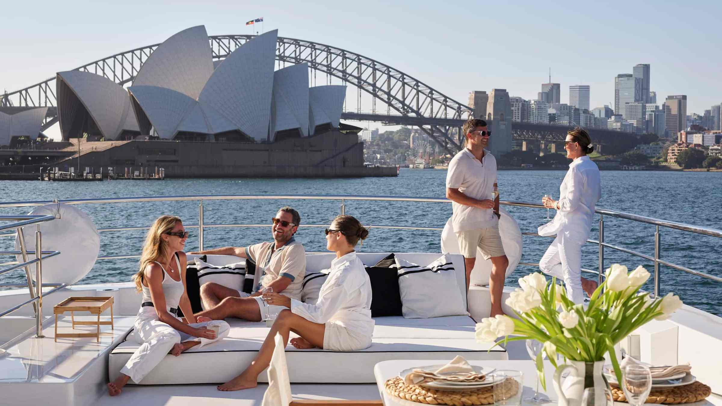People relaxing on a yacht with the Sydney Opera House and Harbour Bridge in the background.