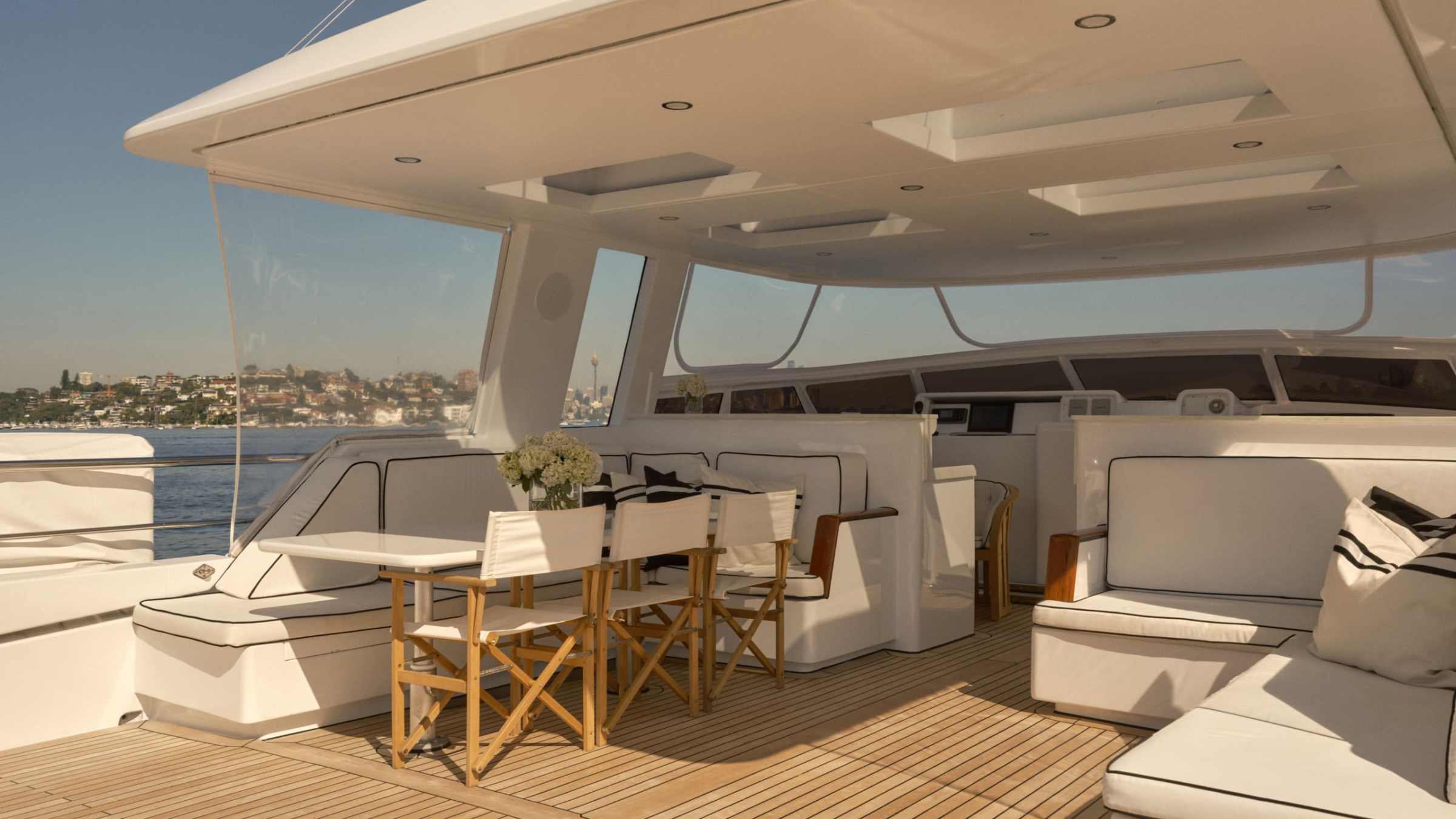 Spacious yacht deck with cushioned seating, dining table, and scenic ocean view.