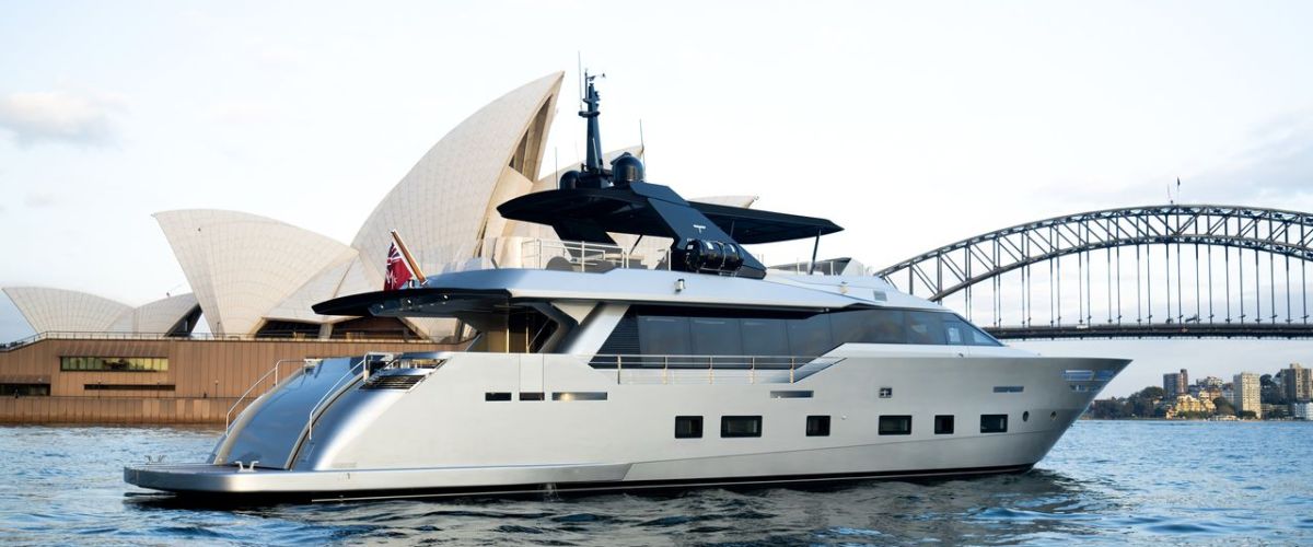 Luxury yacht on water with Sydney Opera House and bridge in background.