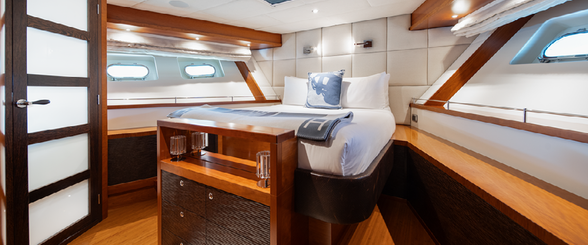 Luxurious yacht bedroom with wooden interior and white bedding.