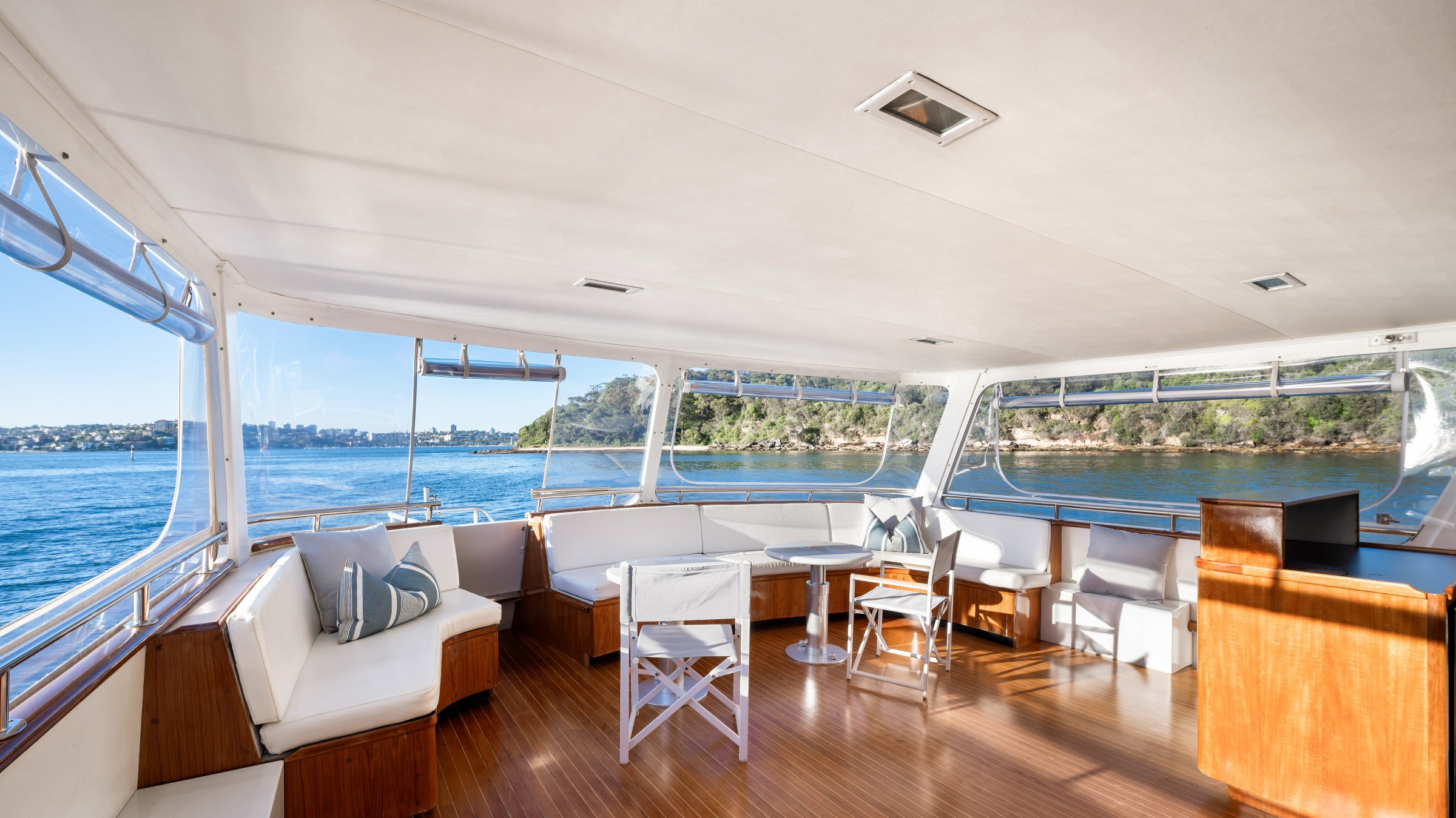 Spacious yacht interior with wooden flooring and panoramic ocean view.