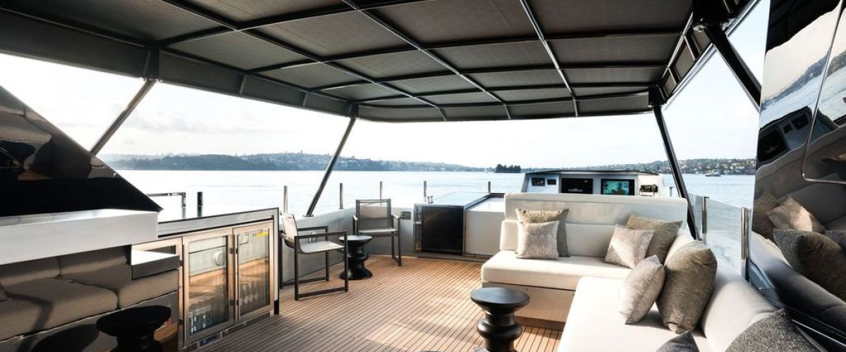 Luxurious yacht deck with modern furniture, covered seating area, and water views.