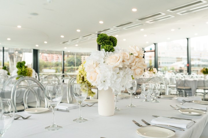 Elegant table setting with white flowers and glassware in a bright room.