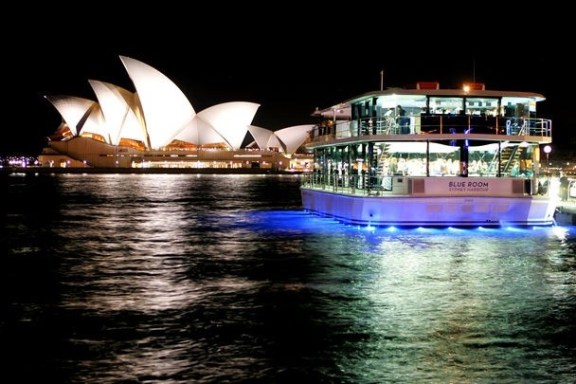 Sydney Opera House and a lit boat at night on the water.