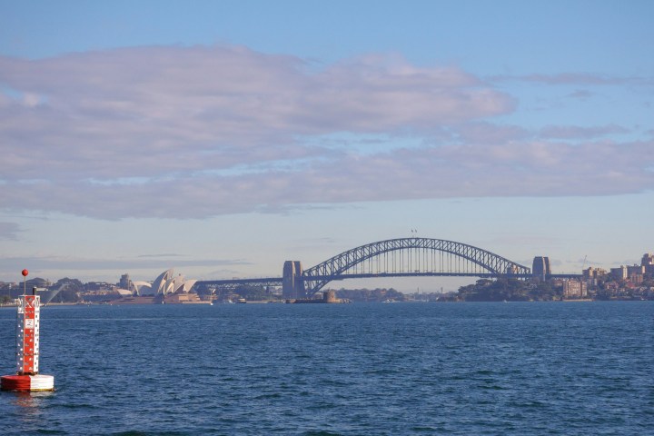 Sydney Harbour with a bridge and opera house in the distance.